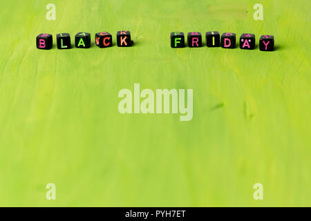 Text `Black Friday` composed of small black blocks with colored letters on green background. Stock Photo